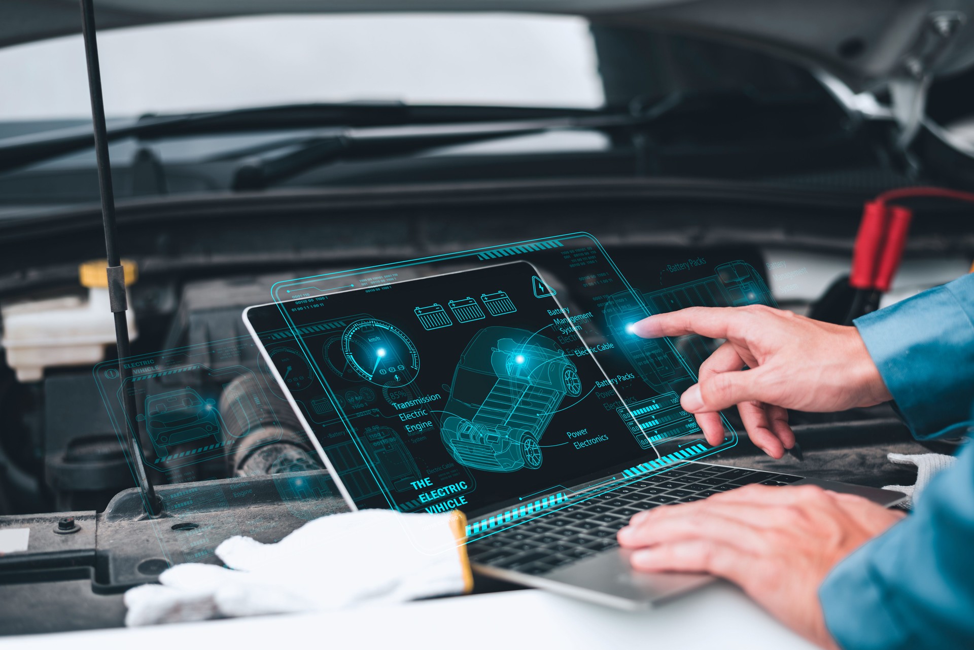 Mechanic working close to an automobile engine while using a laptop. A screen-based automotive diagnostic application. idea of a car service